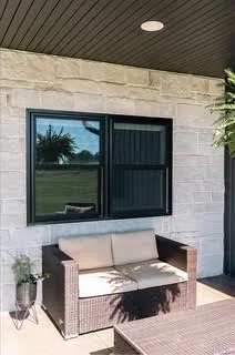 Black casement windows installed over a covered stone patio
